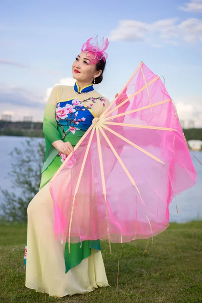 川岸にファンを持つ伝統的なチャイナ ドレスで美しい中国の女の子 — ストック写真