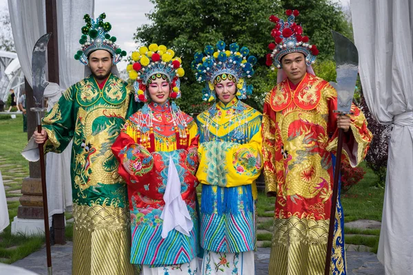 Grupp av fyra asiatiska människor män och kvinnor står i rad och hälsning utomhus i traditionella kinesiska dräkter — Stockfoto