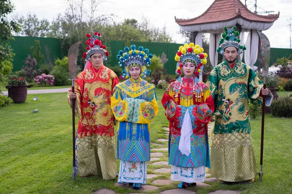 Grupp av fyra asiatiska människor män och kvinnor står i rad och hälsning utomhus i traditionella kinesiska dräkter — Stockfoto