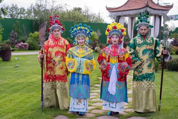 Grupp av fyra asiatiska människor män och kvinnor står i rad och hälsning utomhus i traditionella kinesiska dräkter — Stockfoto