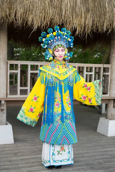 Красива китайська дівчина в традиційній китайській сукні з довгими рукавами і капелюхом, стоячи на відкритому повітрі — стокове фото