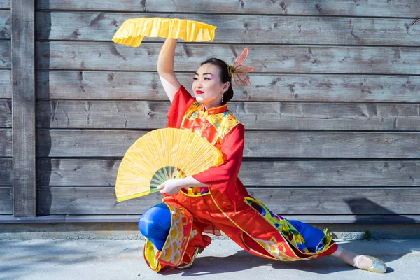 Vacker kvinna i kinesiska traditionell dräkt med två stora gula fans — Stockfoto
