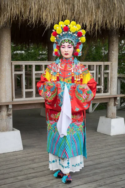 Vacker kinesisk flicka i traditionell kinesisk klänning med långa ärmar och hatt stående utomhus — Stockfoto