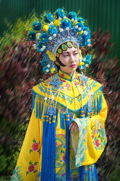 Mooie Chinees meisje in traditionele chinese jurk met lange mouwen en hoed staande buiten — Stockfoto
