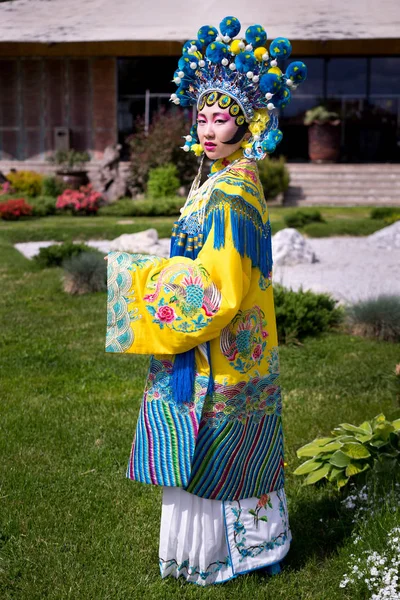 Красива китайська дівчина в традиційній китайській сукні з довгими рукавами і капелюхом, стоячи на відкритому повітрі — стокове фото