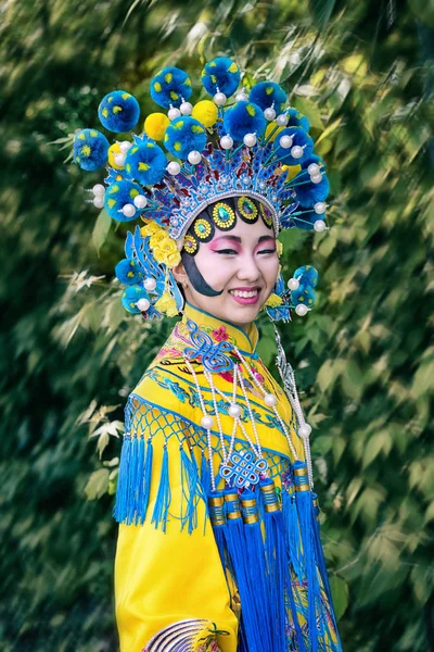 Bella ragazza cinese in abito tradizionale cinese con maniche lunghe e cappello in piedi all'aperto — Foto Stock
