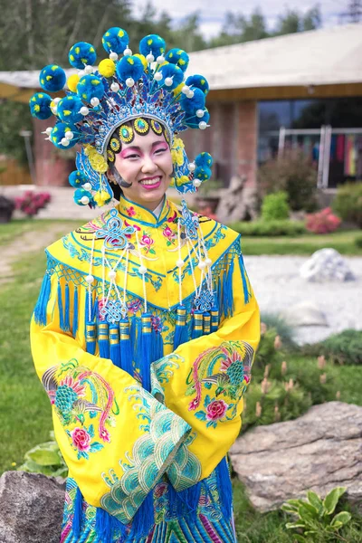 Vacker kinesisk flicka i traditionell kinesisk klänning med långa ärmar och hatt stående utomhus — Stockfoto
