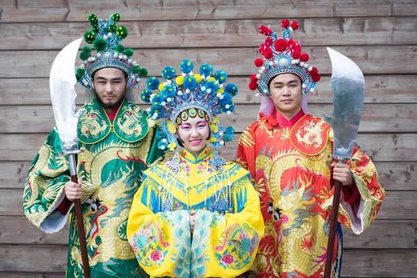 Група з трьох азіатських людей чоловіків і жінок, що стоять поспіль і вітаються на відкритому повітрі в традиційних китайських костюмах — стокове фото