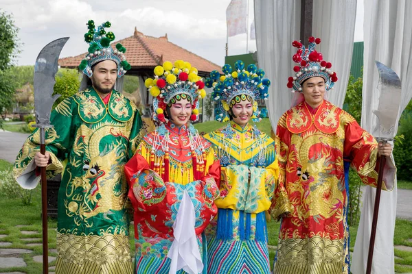 Група з чотирьох азіатських людей чоловіків і жінок, що стоять поспіль і вітають на відкритому повітрі в традиційних китайських костюмах — стокове фото