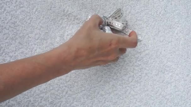 Жіноча рука висить різдвяні дзвіночки, лук і вентилятори обрамляють рядок на блискучому фоні з місцем для тексту — стокове відео