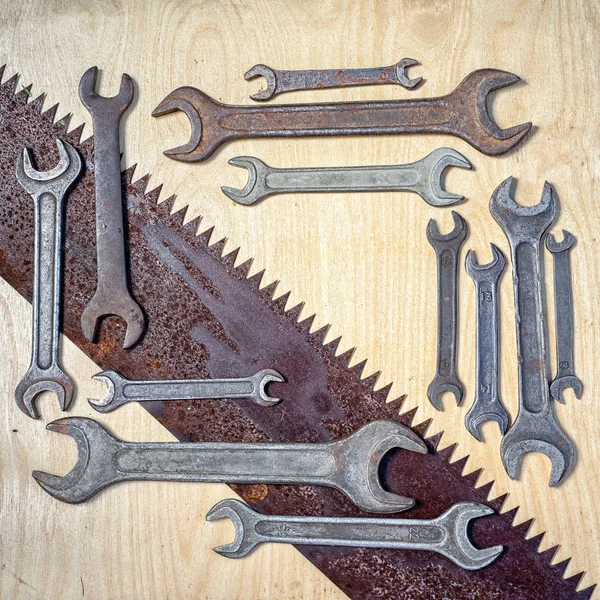 flat lay frame wiith many old rustic wrenches and laying diagonal saw with copy space for your text. suitable as a background for father\'s day congrats card or ad in the repair shop.
