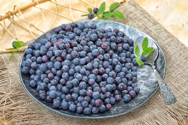 Blueberry di piring dengan sendok di atas meja kayu — Stok Foto
