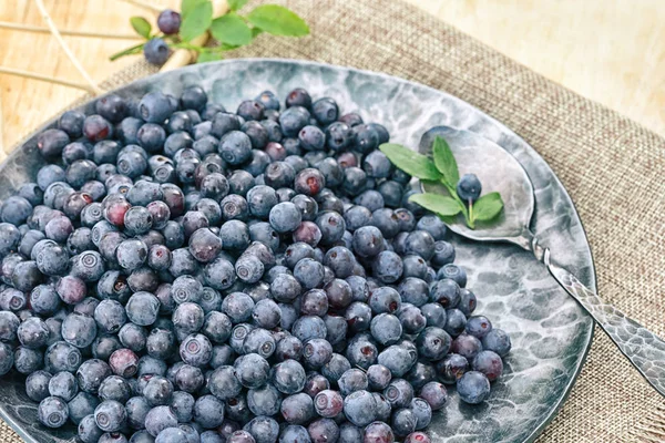 Blueberry di piring palsu dengan sendok di atas meja kayu — Stok Foto