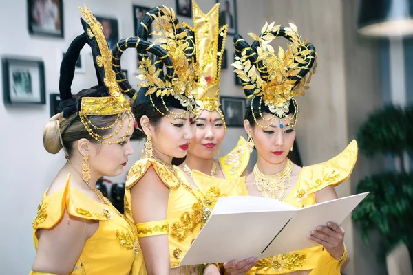 Cuatro mujeres asiáticas actrices en trajes tradicionales tailandeses amarillo lectura libro en blanco con espacio de copia para su texto — Foto de Stock