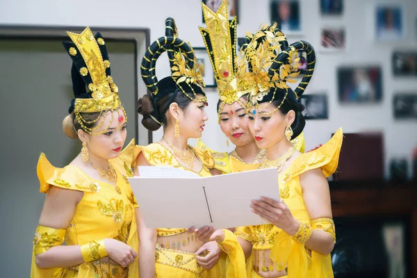Quattro donne asiatiche attrici in costumi tradizionali gialli tailandesi leggere libro bianco con spazio per copiare il testo — Foto Stock