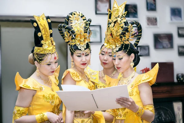 Quattro donne asiatiche attrici in costumi tradizionali gialli tailandesi leggere libro bianco con spazio per copiare il testo — Foto Stock