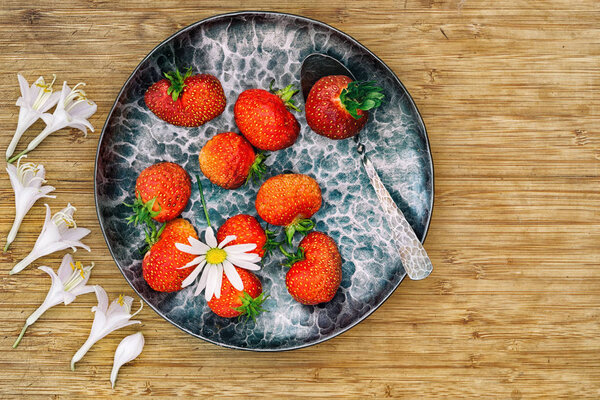 strawberry in a forged metal plate on a wooden table top view with copy space