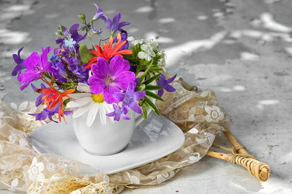 Wilde bloemen boeket met blue bells chamomiles en vergeet mij niet in een kop witte thee met kopie ruimte — Stockfoto