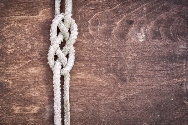 Vecchia corda con nodo nautico su uno sfondo di legno scuro con spazio copia — Foto Stock