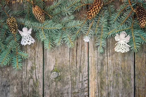 Quadro de natal de ramos de abeto, cones e anjos brancos de malha em uma mesa de madeira. vista superior com espaço de cópia para o seu texto . — Fotografia de Stock