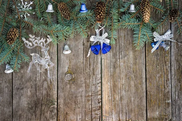 Marco de navidad de ramas de abeto, conos, campanas y juguete de renos en una mesa de madera. vista superior con espacio de copia para su texto . — Foto de Stock