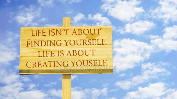 Life isn't about finding yourself, life is about creating yourself. Words on a wooden sign against time lapse clouds in the blue sky. — Stock Video