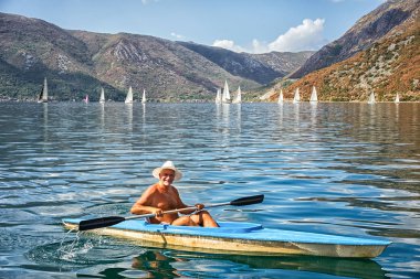Risan, Karadağ-3 Eylül 2017: Kotor Koyu'ndaki yat ile manzara arka kürekler ile bir tekne içinde bilinmeyen bir adam.