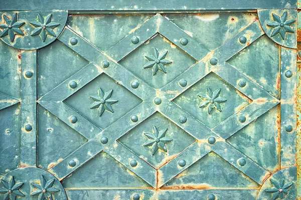 Vista da vicino della vecchia porta in metallo verde arrugginito medievale con motivo rombo con stelle e rivetti come sfondo . — Foto Stock