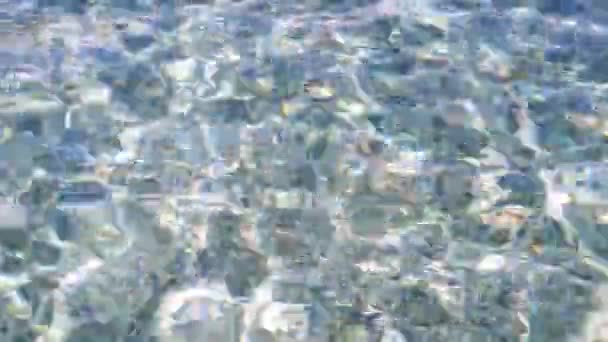 Agua de mar con luz solar en la superficie del agua sobre fondo de guijarros turquesa . — Vídeos de Stock