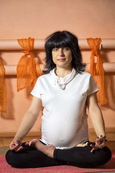 Yoga egzersiz yaparak asana oturan 40 haftalık hamile orta yaşlı beyaz kadın.