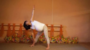 40 haftalık hamile orta yaşlı beyaz kadın yoga yaparken yanlara doğru eğilir egzersizleri