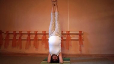 Bacaklarını yoga poz amuda başında dururken ile egzersizleri yapıyor 40 haftalık hamile orta yaşlı beyaz bir kadın. Hızlandırılmış video. 