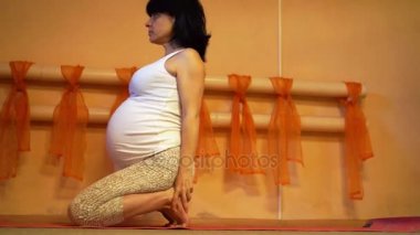 Yoga yaparken 40 haftalık hamile orta yaşlı beyaz kadın sağlıklı yaşam konsepti deve poz egzersizleri.