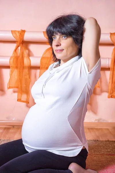 Gebelik Yoga ve Fitness kavramı. Sağlıklı annelik yaşam kavramı. diz yoga egzersiz yaparak gomukasana asana kucağında oturan 40 haftalık hamile orta yaşlı beyaz kadın.