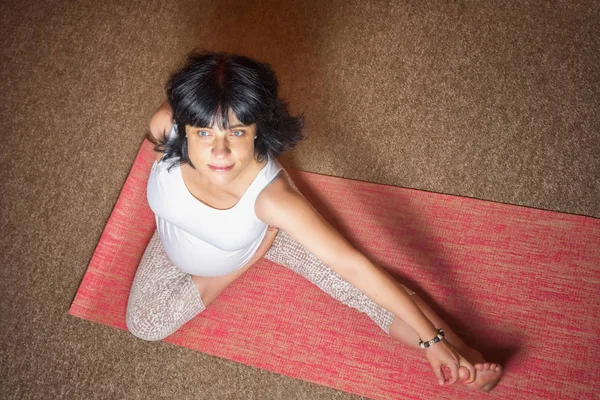 40 тижнів вагітна середнього віку біла жінка сидить в Асані, роблячи вправи на йогу. Вид зверху, простір для копіювання вашого тексту . — стокове фото