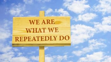 Biz tekrar tekrar ne vardır. Kelime zaman atlamalı bulutlar mavi gökyüzünde karşı ahşap bir işaret üstünde.