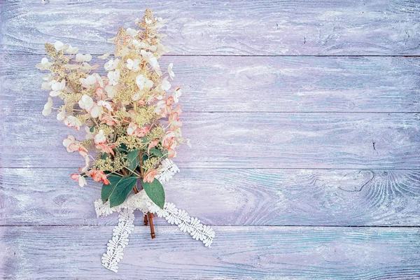 Ramo de hortensias de color rosa-blanco en una mesa de madera, atado con una cinta de encaje, vista superior con espacio de copia para su texto. adecuado como fondo de tarjeta de invitación de boda o cumpleaños . —  Fotos de Stock