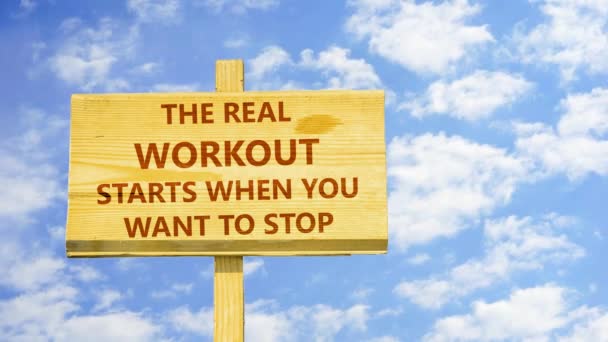 The real workout starts when you want to stop. Words on a wooden sign against time lapse clouds in the blue sky. — Stock Video