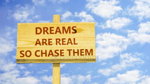 Dreams are real, so chase them. Words on a wooden sign against time lapse clouds in the blue sky. — Stock Video