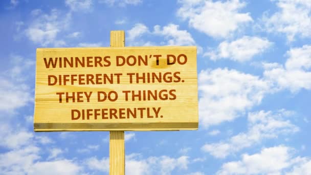 Los ganadores no hacen cosas diferentes. Hacen las cosas de manera diferente. Palabras en un letrero de madera contra nubes de lapso de tiempo en el cielo azul . — Vídeos de Stock