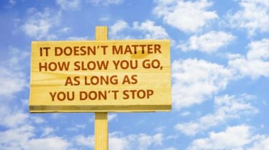 Sakın durma sürece ne kadar yavaş gitmek önemli değil. Kelime zaman atlamalı bulutlar mavi gökyüzünde karşı ahşap bir işaret üstünde.
