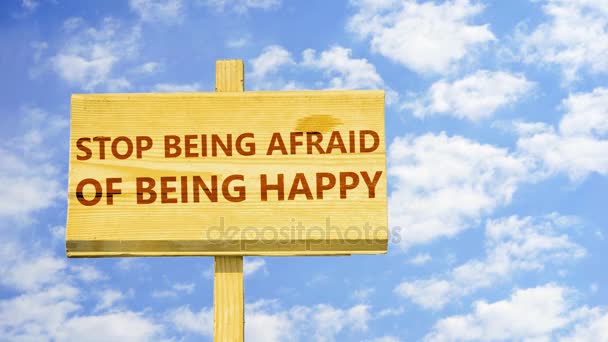 Hört auf, Angst davor zu haben, glücklich zu sein. Worte auf einem Holzschild gegen Zeitraffer-Wolken am blauen Himmel. — Stockvideo