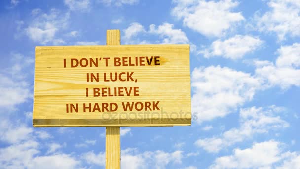 Δεν πιστεύω στην τύχη. Πιστεύω στη σκληρή δουλειά. Λόγια σχετικά με μια ξύλινη πινακίδα κατά ώρα λήξη σύννεφα στο μπλε του ουρανού. — Αρχείο Βίντεο