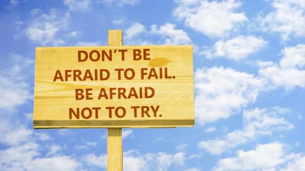 Wees niet bang om te mislukken. Worden bang om niet te proberen. Woorden op een houten bord tegen tijd vervallen wolken in de blauwe hemel. — Stockvideo