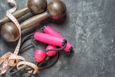 Metniniz için kopya alanı görünümüyle dambıl, santimetre teyp ve genişletici bir spor kavramsal zemin olarak karanlık çimento zemin üzerine top.