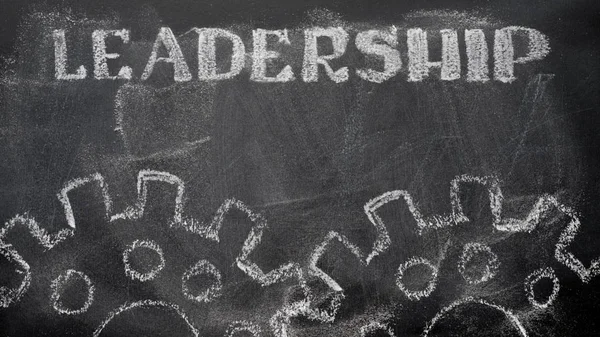 The blackboard writing with chalk and the concept of business, the text `Leadership`, and two chalk silhouette drawing gears.