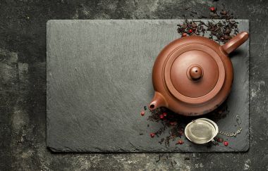 Geleneksel kahverengi kil çaydanlık siyah taş tepsi, kuru meyveler ve küçük chocolades ile Çin siyah çay. Kopya alanı ile Üstten Görünüm.