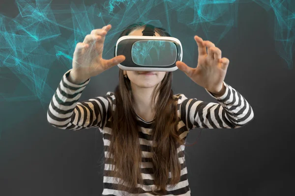 Teenager caucasian girl looking at Virtual Reality Glasses over abstract futuristic modern technology background with lines. Virtual reality, vr box. Studio, indoors.