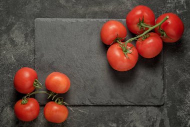 taze, olgun küçük siyah çimento zemin, metniniz için kopya alanı ile üstten görünüm üzerinde döşeme siyah taş tepsi üzerinde domates demet
