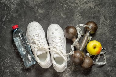 arka plan siyah bir arka plan kopya alanı ile spor ayakkabı, halter, şişe suyu, elma ve sentimeter teyp üstten görünüm spor. sağlıklı yaşam konsepti.